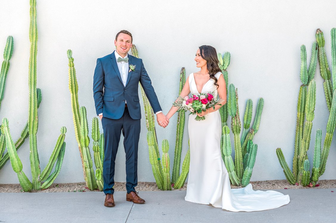 Bride and groom walking hand in hand with Camelback Mountain behind them at Andaz Scottsdale
