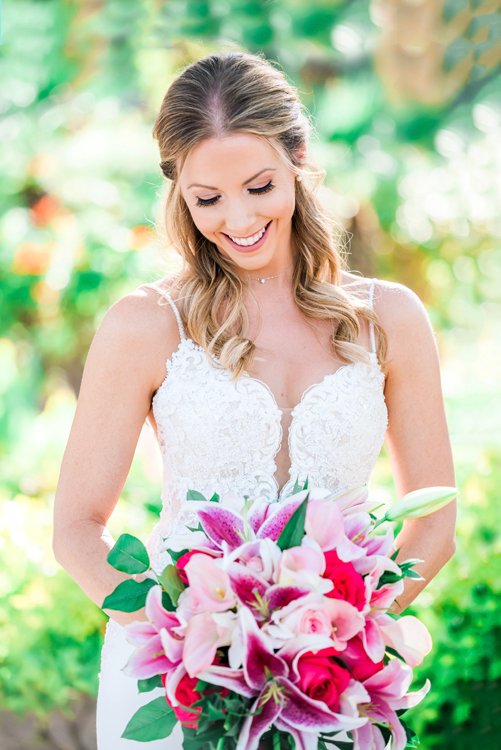 Bride smiling holding pink bouquet outdoors