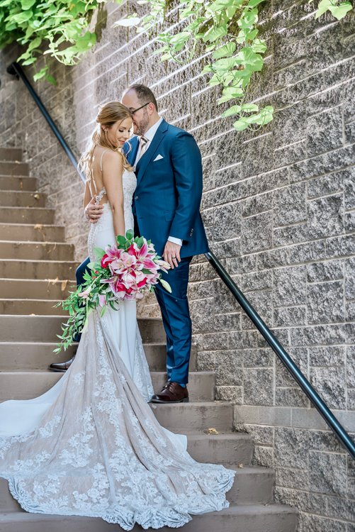 Bride and groom standing on staircase with pink bouquet