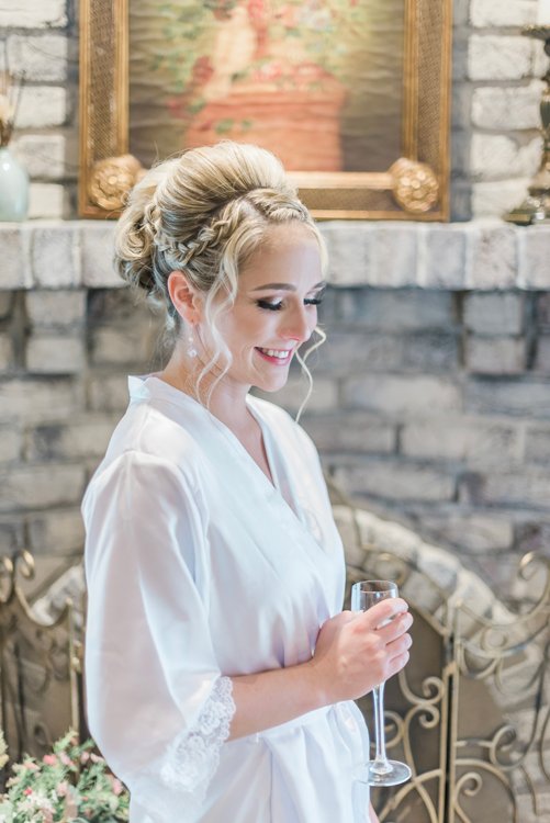 Bride smiling while getting ready in white robe