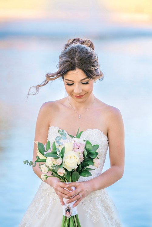 Bride holding bouquet with soft ocean or lake background