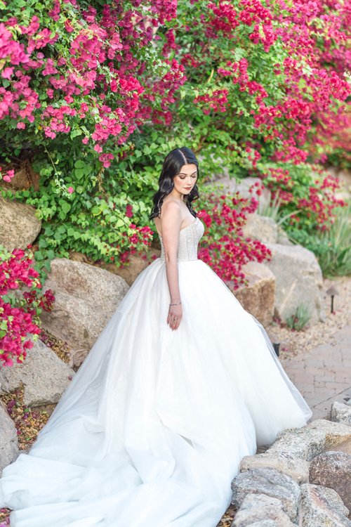 Bride standing outdoors in full ballgown surrounded by flowers