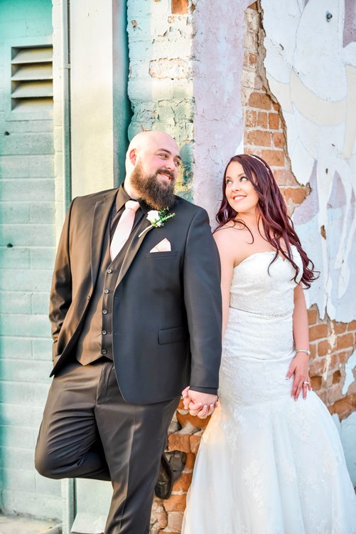 Bride and groom posing together by rustic turquoise doors