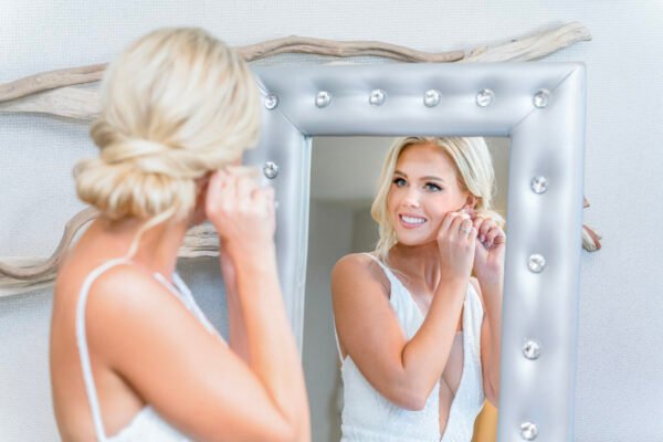 Bride adjusting earrings in silver studded mirror