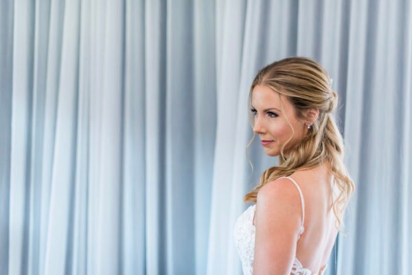 Bride standing by window wearing white robe