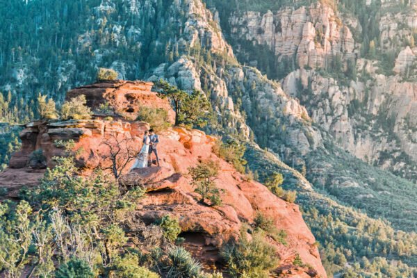 Couple standing on red rock cliff in Arizona