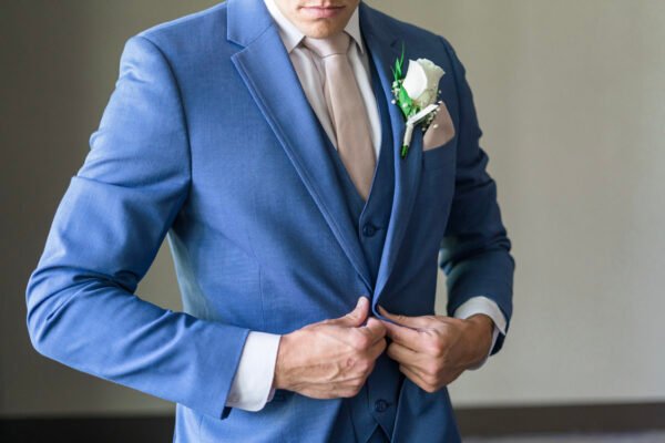Groom adjusting blue suit jacket detail