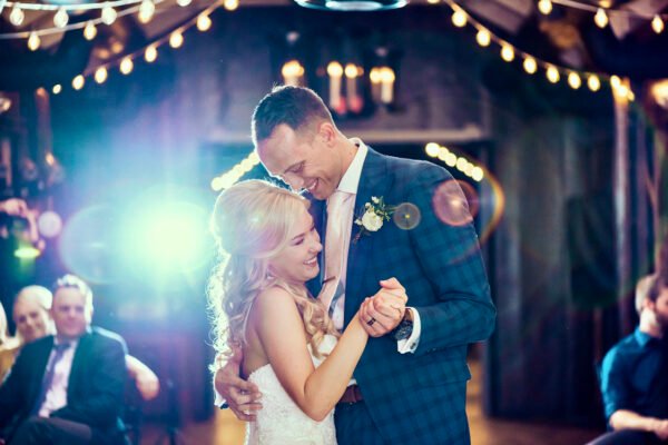 Bride and groom dancing with string lights behind them