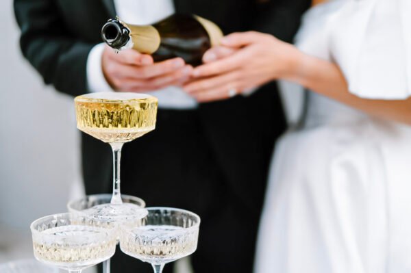 Champagne being poured into stacked glasses at wedding