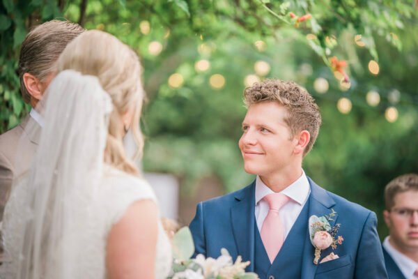 Groom smiling at bride during outdoor ceremony