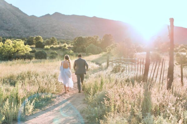 Arizona wedding photographer documenting a bride and groom walking through a golden field at sunset.